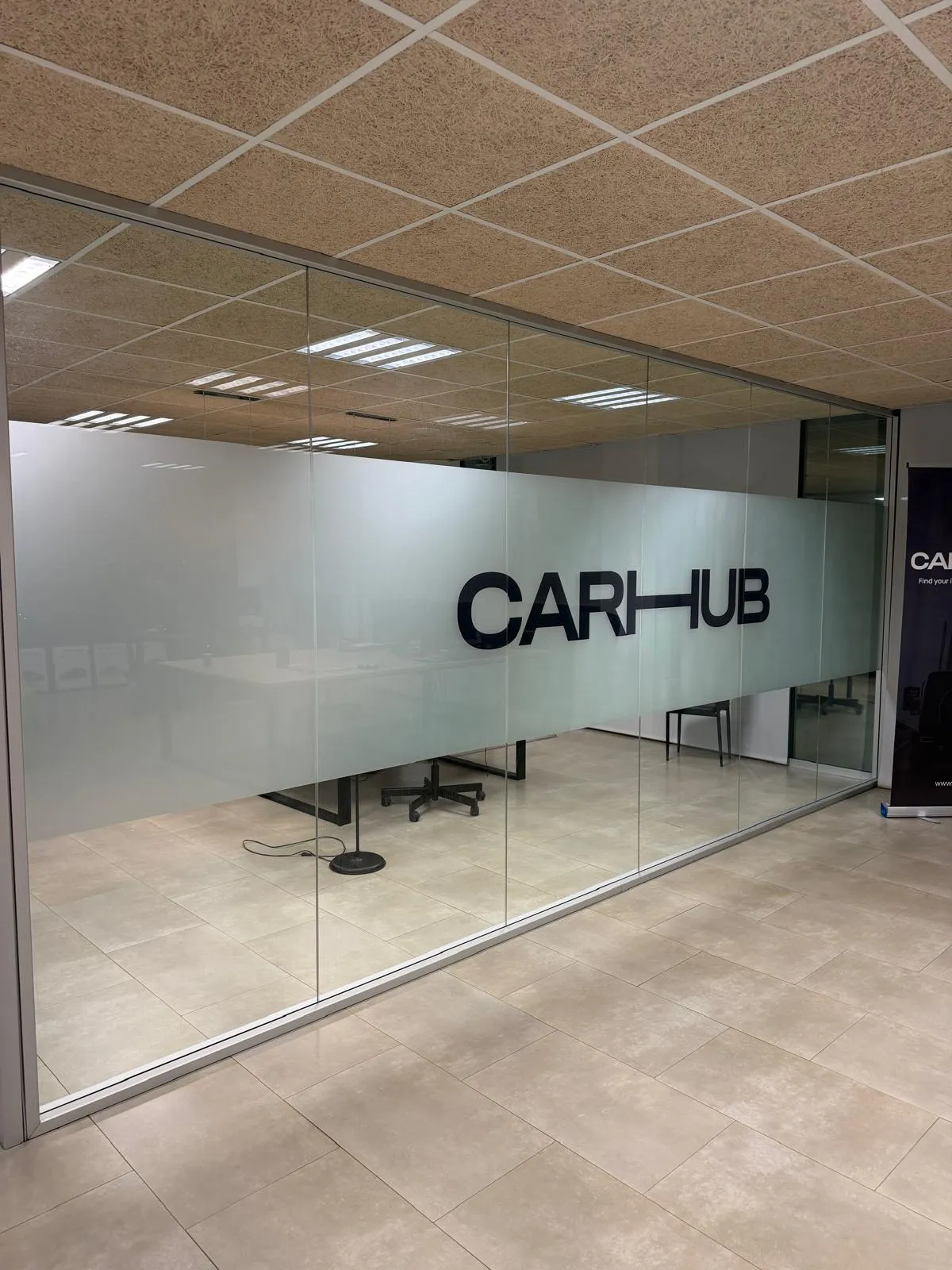 Mampara de cristal de oficina con vinilo impreso efecto ácido y el logotipo CARHUB en negro