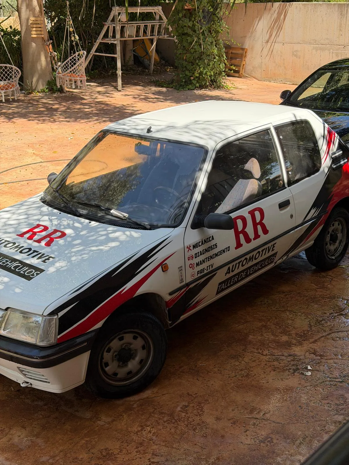 Coche blanco rotulado con la marca RR Automotive en rojo y negro y el listado de servicios del taller