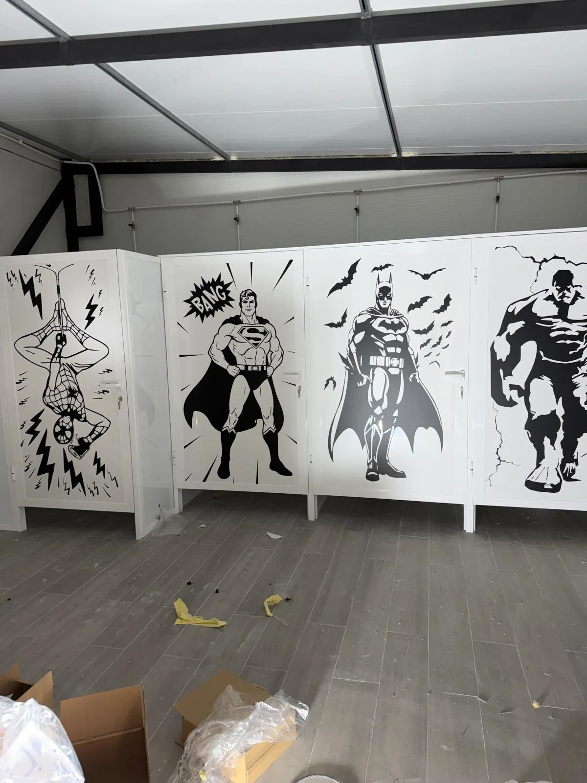 Serie de paneles blancos con siluetas de superhéroes en vinilo de corte negro
